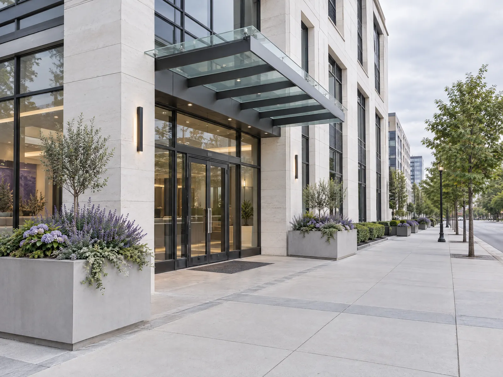 Modern medical building entrance with a glass canopy and lavender planters on a wide sidewalk